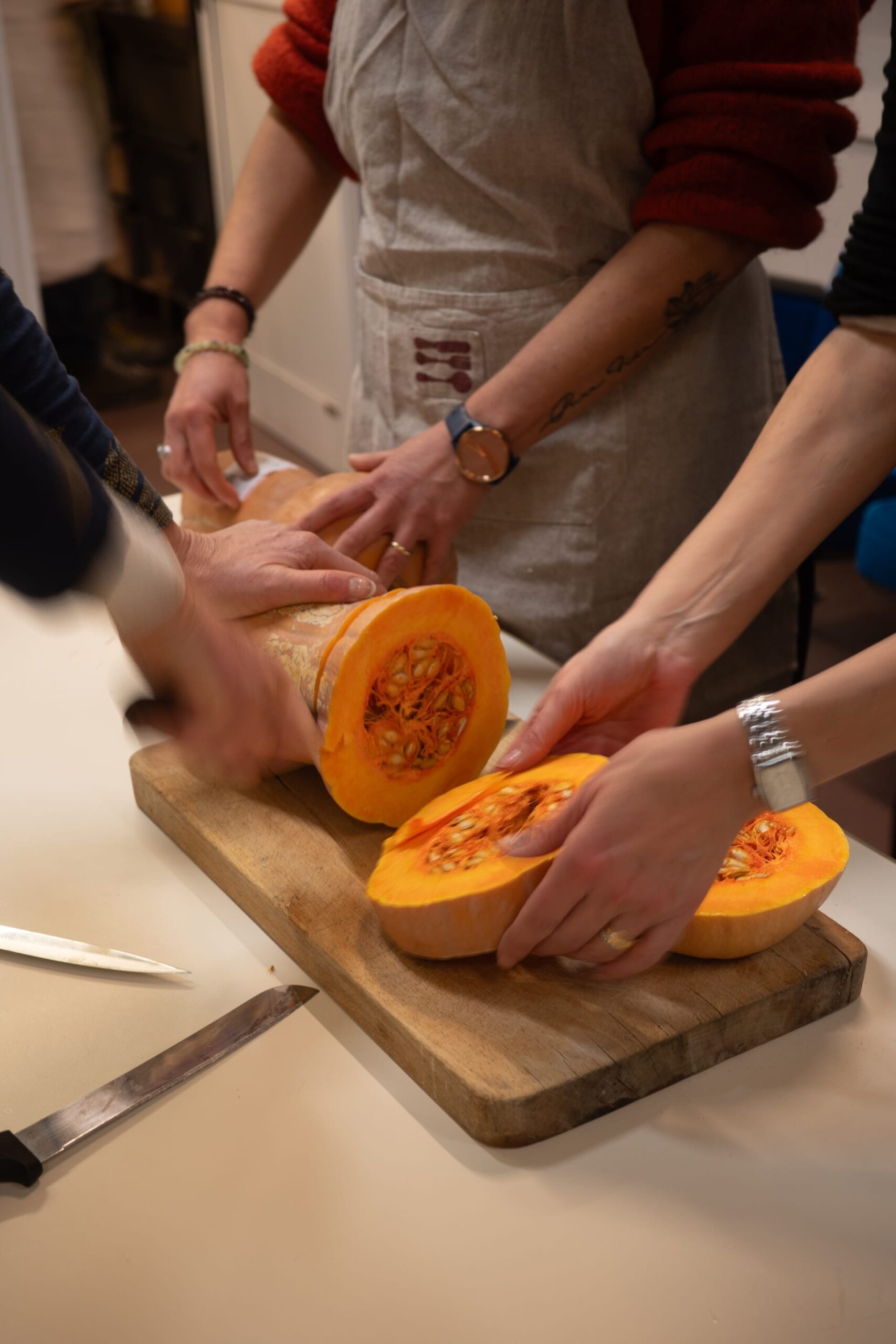Hands of multiple people cutting a big pumpkin